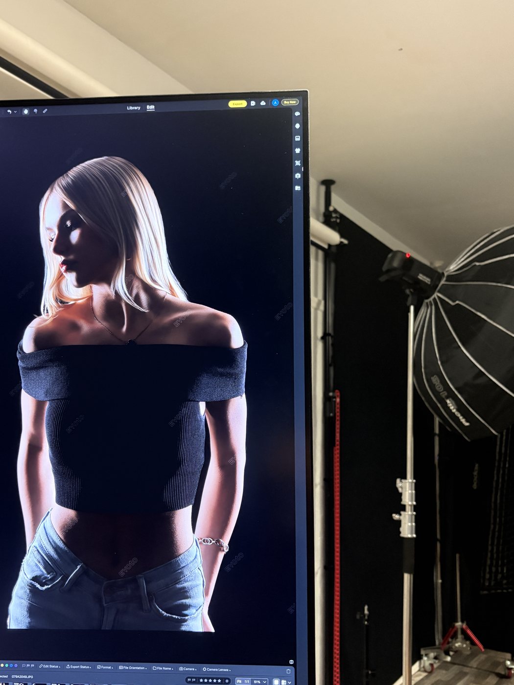 A studio portrait of Madeline on the editing monitor beside a softbox