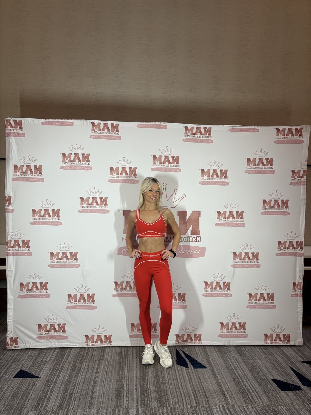 Madeline in a red Alo set in front of the National American Miss backdrop